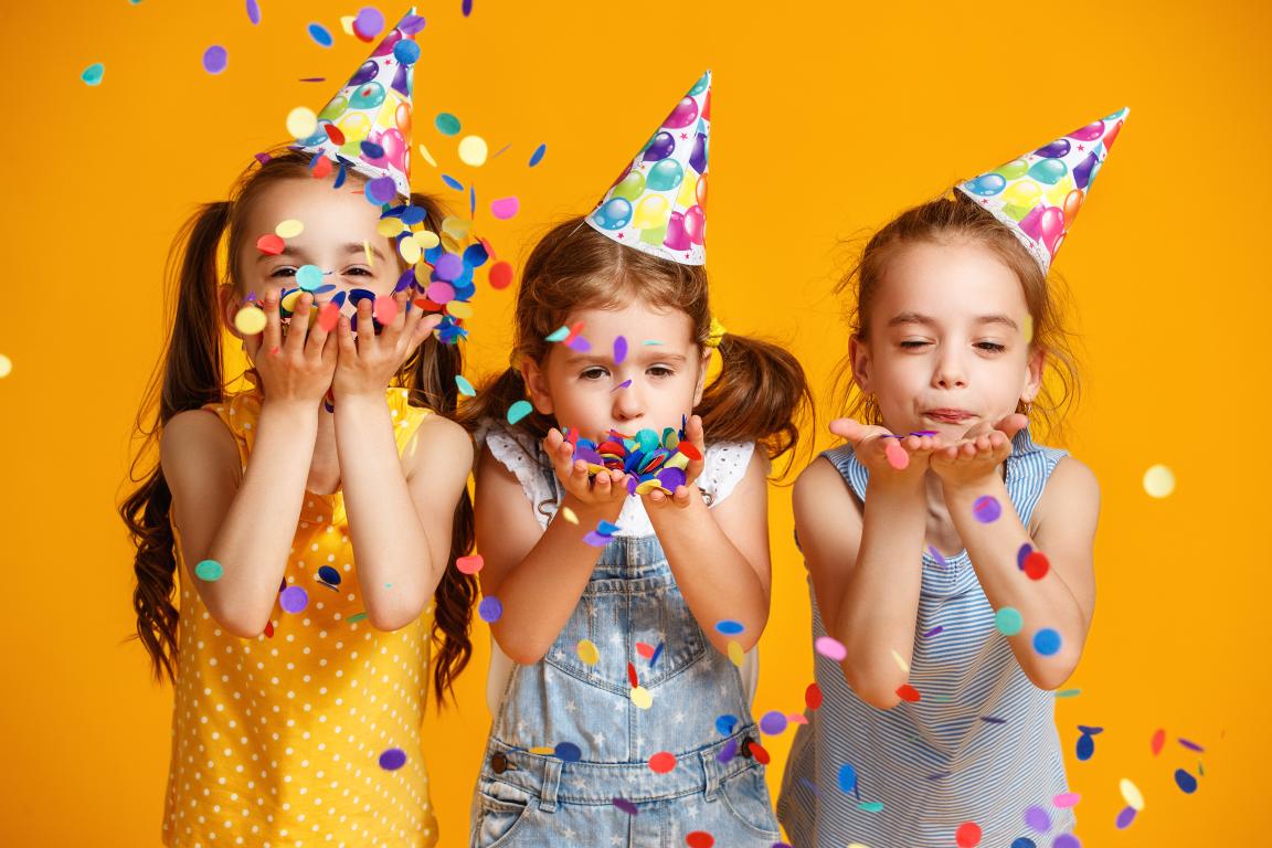 Drei Kinder mit Hut und Konfetti